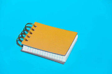 Yellow hardcover spiral bound notebook on blue backdrop