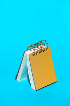 Yellow hardcover spiral bound notebook on blue backdrop