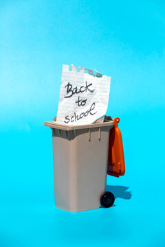 Paper with message back to school placed in miniature dust bin