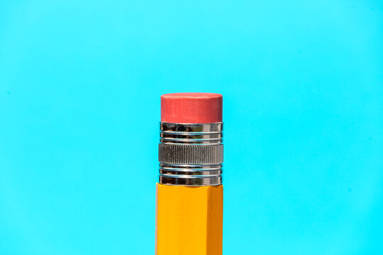 Bright yellow pencil with eraser on top in blue studio