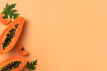 Cut Papaya over orange table background for tropical fruit design concept.