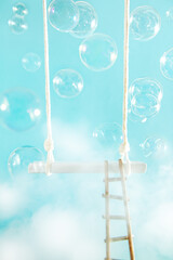 Swing with ladder and soap bubbles in the clouds on a blue background.