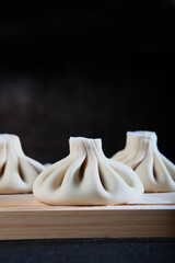 Cooking dumplings or cooking khinkali. Traditional Georgian dish. Dumplings are made by hand. Close-up. Vertical photo. Black background.Copy space.