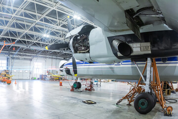 Transport turboprop airplane in the hangar. Aircraft under maintenance. Checking mechanical systems...