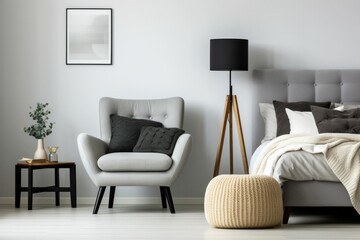 Grey armchair and stool near bed with headboard in bedroom interior with black lamp. Generative AI