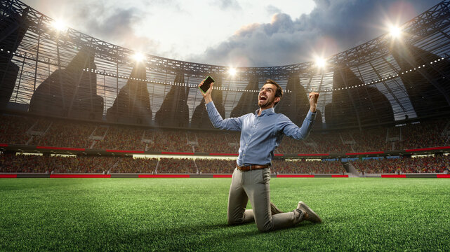 Man standing on knees on football arena, holding mobile phone and celebrating win of money. Successful betting. 3d render. Concept of sport, fan, betting and finances, gambling, bookmaker