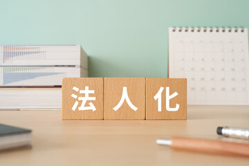 法人化と書かれたブロックが置かれたデスク