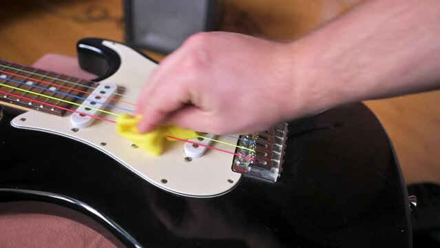 Man cleaning black electric guitar with white pickups. Guitar service concept. 4k video footage UHD 3840x2160