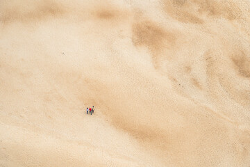 Fototapeta na wymiar Aerial view of deserted sandy beach with people walking
