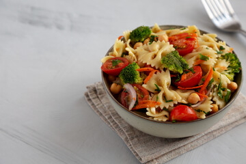 Yummy Homemade Vegan Pasta Salad with Tomato, Onion, Carrot, Broccoli, Chickpeas and Parsley in a Bowl, side view. Copy space.
