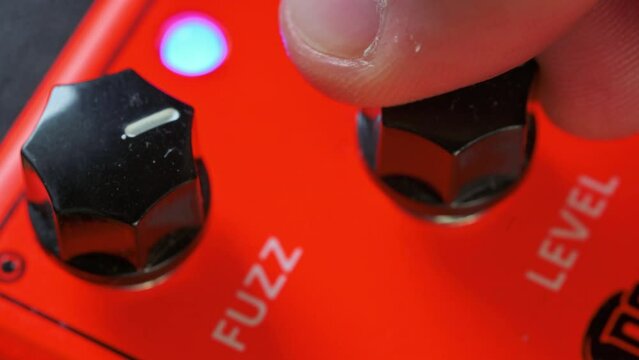 Man tuning knobs on fuzz guitar pedal effect. 4k video footage UHD 3840x2160
