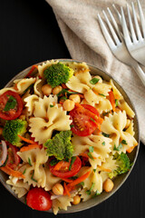 Yummy Homemade Vegan Pasta Salad with Tomato, Onion, Carrot, Broccoli, Chickpeas and Parsley in a Bowl, top view.