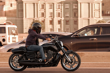 Fototapeta na wymiar A man rides a black stylish cruising motorcycle around the city. Motorcyclist travels on a beautiful motorbike, lifestyle.