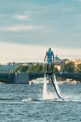 A man takes off above the water on a flyboard in the city river. A sportsman is engaged in an...