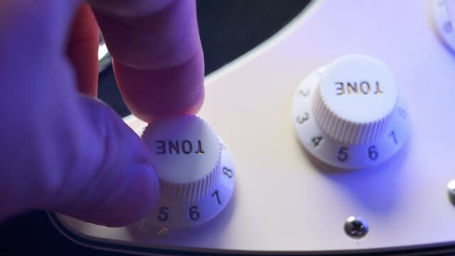 Man adjusting sound tone knob on electric guitar. 4k video footage UHD 3840x2160
