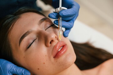 Cosmetologist does injection for lips augmentation. Women's cosmetology in the beauty salon