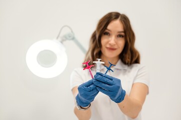 White wall. Cosmetologist holding syringes for injection lips augmentation. Women's cosmetology in...