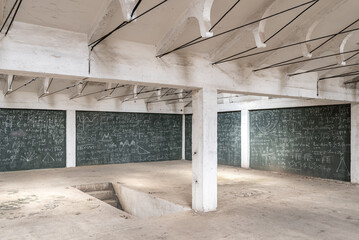 Empty white hall of an industrial building with walls crammed with formulas on a green chalkboard,...