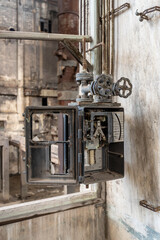 Close-up of an industrial broken appliance with iron dials in a dilapidated building with earth tones