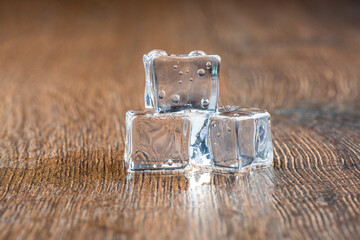 Several melted ice cubes on a wooden background.