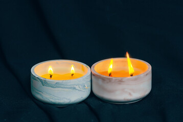 Fototapeta na wymiar Decorative candles burn in the apartment on black background