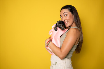 Happy girl received an adorable puppy as a gift - isolated on yellow background.