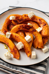 Baked pumpkin slices with spices and cubes of feta cheese. Pumpkin dishes.