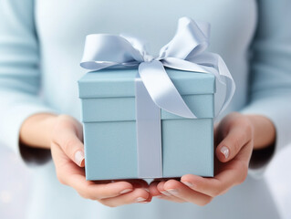 Decorative festive gift box with a bow in women's hands