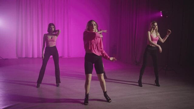 Women learn high heel dance choreography with a trainer. Group class with sexy dance for body flexibility. High quality 4k footage