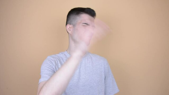 Dismissive Gesture - Young Man in Gray T-Shirt Waving Indifferently on Solid Background