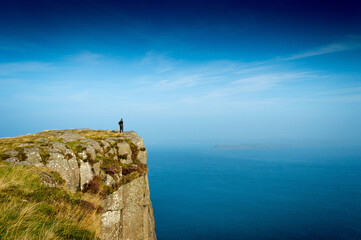 Fototapeta na wymiar A solo hiker on the high cliffs of Fair Head in County Antrim in Northern Ireland 