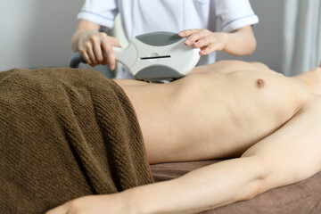 Fototapeta premium お腹の脱毛の施術を受ける若い男性 