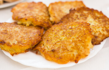 Fried grated potato pancakes with sour cream on white plate