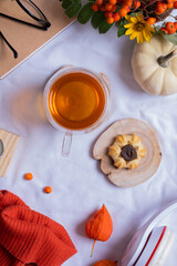 Cup of tea with cookies and autumn cozy decor with sweater and pumpkins top view, flat lay