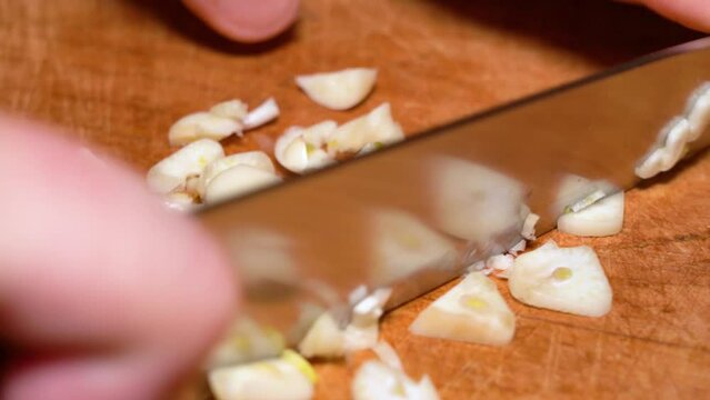 male hands cut garlic on a wooden board. close-up