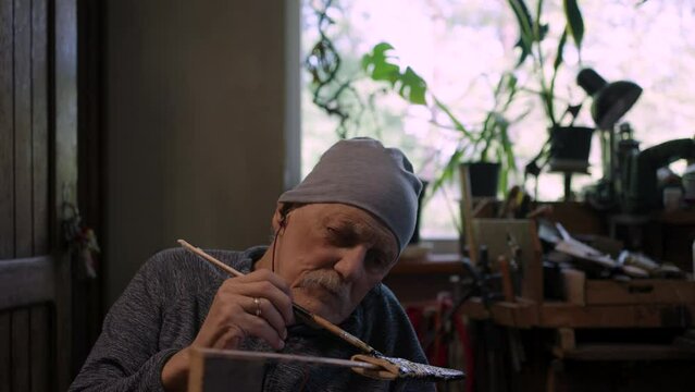 Elderly male master works in his workshop restoring japanese deba knife sheath