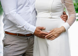 Groom holding his hands on bride's pregnant belly during wedding