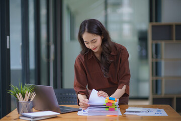 Businesswoman hands working in Stacks of paper files for searching and checking unfinished document...