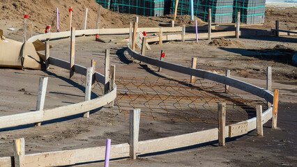 Curved hardboard forms with wooden stakes in place for pouring of concrete to make a sidewalk in a...