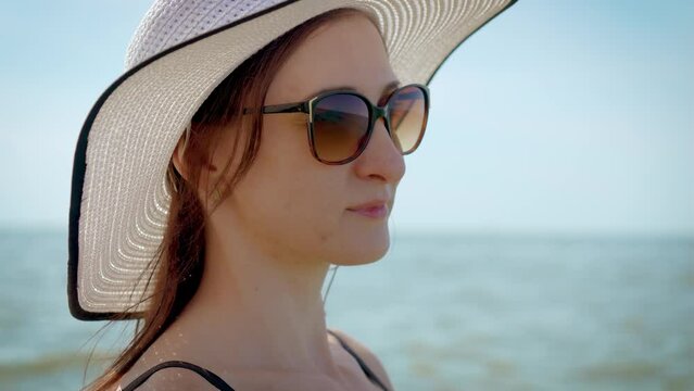 Face attractive brunette woman at sea sunset in sunglasses and stylish white hat. Resting active healthy lifestyle and wellness