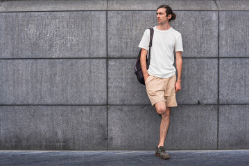 Handsome Young man  white t-shirt leaning against gray exposed concrete wall  background and wallpaper texture Modern loft empty cement. copy space city.