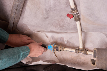 Insulating water supply pipes in basement of rural house on eve of winter frosts.