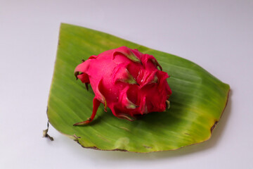 Dragon fruit on banana leaf isolated on white background. Ripe pitahaya