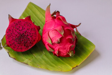 Red flesh dragon fruit, Pitaya or Pitahaya, cut into slices ready to eat, placed on a green banana...