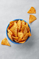 Tortilla chips in a bowl on a gray background viewed from above. Mexican fast food. Top view