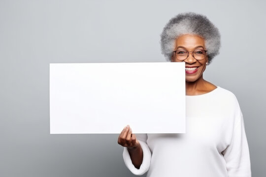 Happy old black woman holding blank white banner sign, isolated studio portrait .