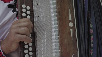 Man is playing on old Russian accordion.