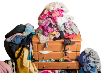 open chest drawers with drop-down clothes and piles of clothes around in a mess.Close-up