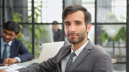 male boss against the background of her colleagues looks at the camera in a modern office