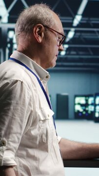 Vertical video Developer in server room expertly managing data while navigating through industrial mainframes. Expert ensuring flawless cybersecurity guard, optimizing systems using green screen